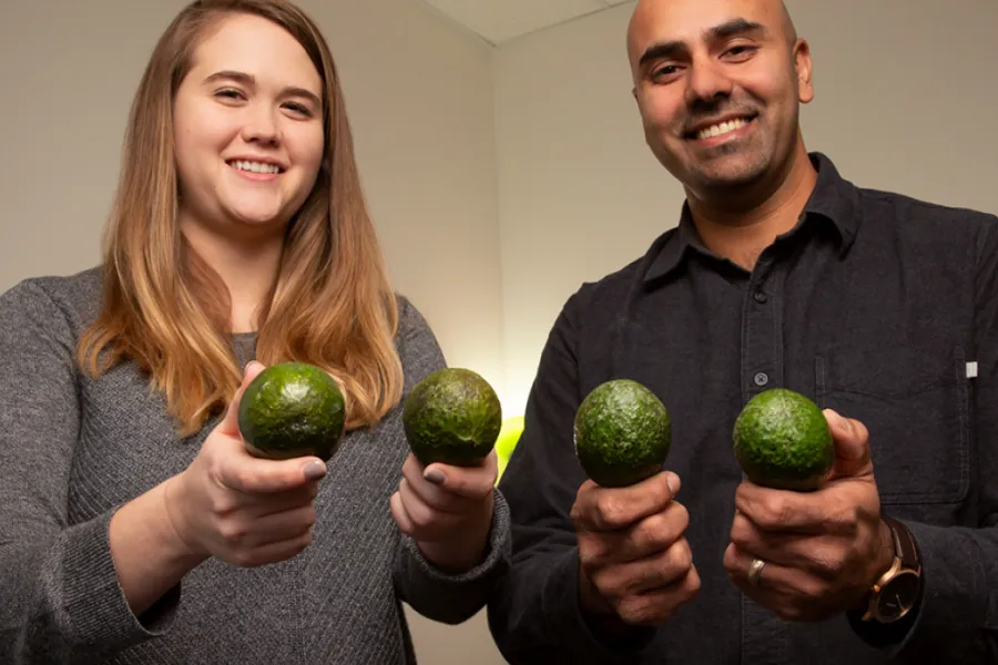 Graduate student Caitlyn Edwards and professor Naiman Khan hold avocados 