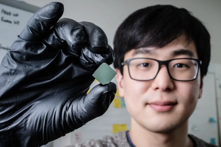 llinois mechanical science and engineering student and lead author of a new study Benjamin Sohn holds a device that uses sound waves to produce optical diodes tiny enough to fit onto a computer chip. 