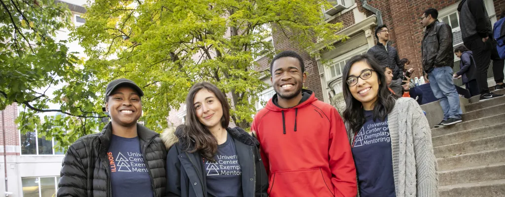 Group of graduate students participating in the University Center of Exemplary Mentoring pose in front of Coble Hall.