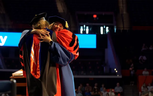 graduate and faculty advisor embrace in celebration