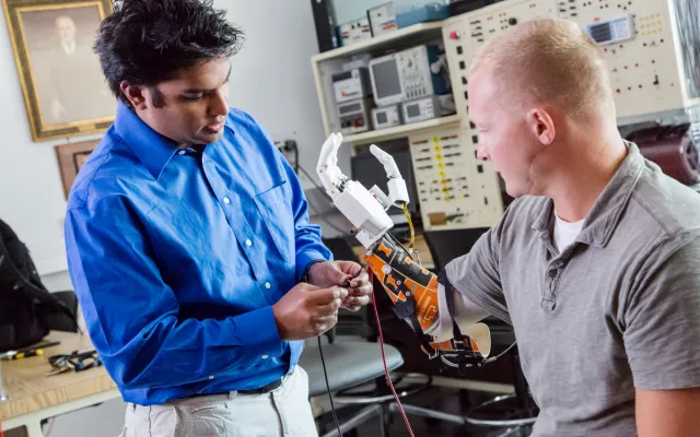  Dr. Akhtar (left) fits Retired Army Sgt. Garrett Anderson, who lost his hand and most of his forearm from an IED blast in Iraq, with a Psyonic prosthetic hand. 