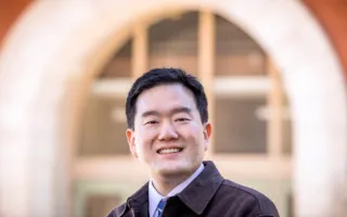 Graduate student Junghwan Kim stands in front of a building on the Illinois campus.