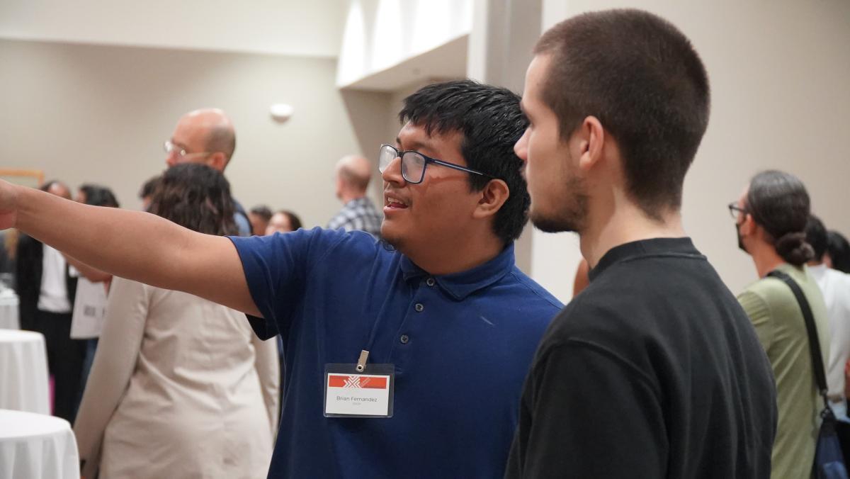 A student explains their work at a poster presentation session.