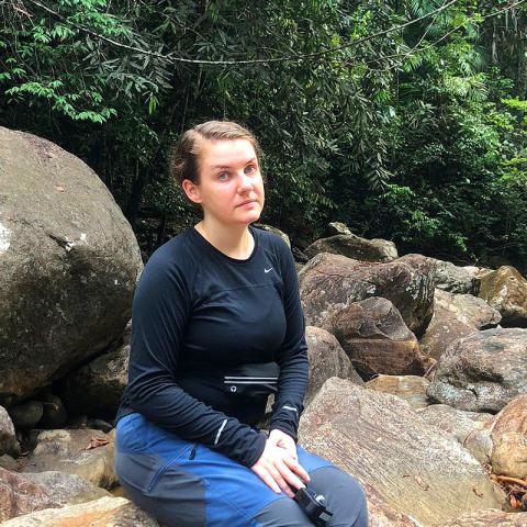 Emma Lundin photographed sitting on a rock in the rainforest. 